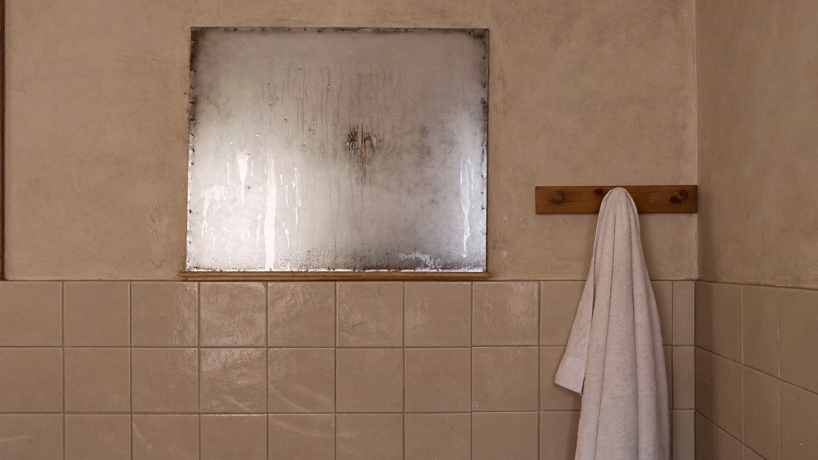 Baño tras la ducha con el espejo y los azulejos superiores empañados por el vapor