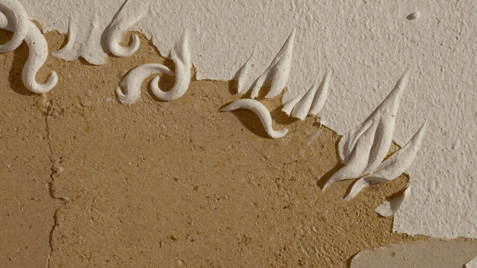 Primer plano de pintura levantada y desconchada despegándose de una pared con humedad