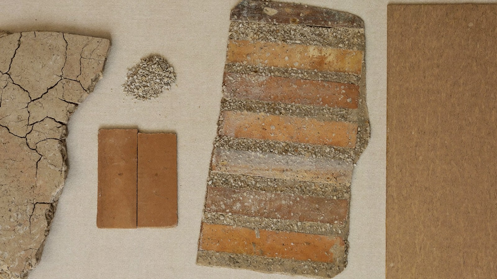 Muestras de materiales de construcción sobre lino: yeso agrietado, ladrillo con mortero, árido fino y rasilla cerámica