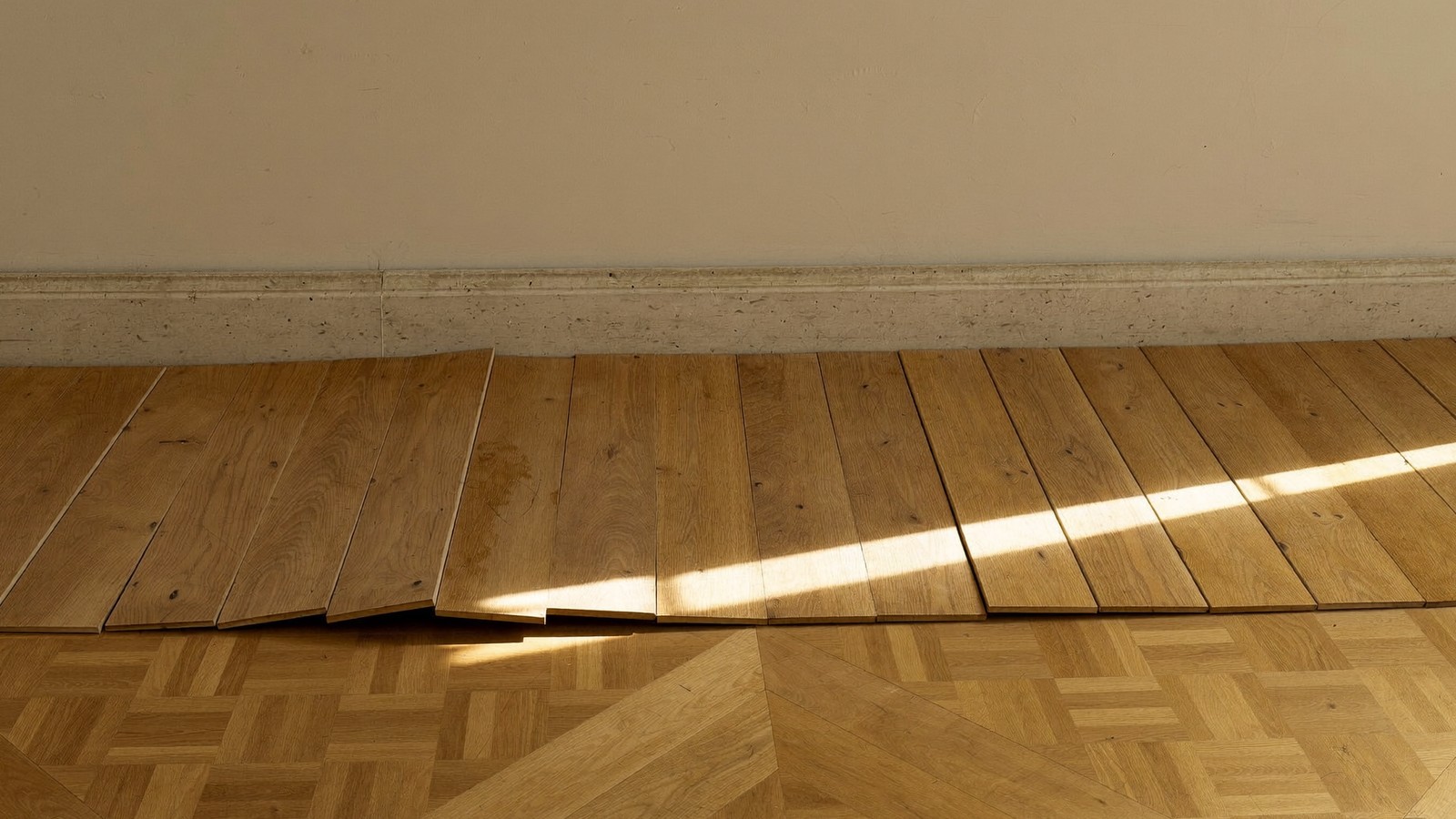 Lamas de parquet de roble abombadas y levantadas por la humedad junto a la pared