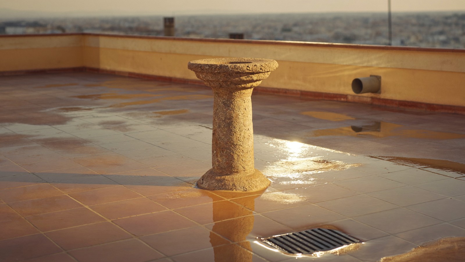 Terraza plana con agua de lluvia encharcada sobre las baldosas cerca del sumidero